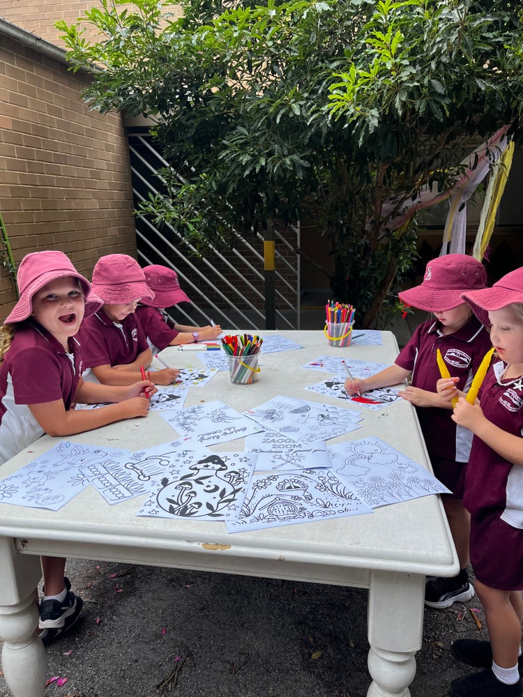 Five students colouring in at a table together.