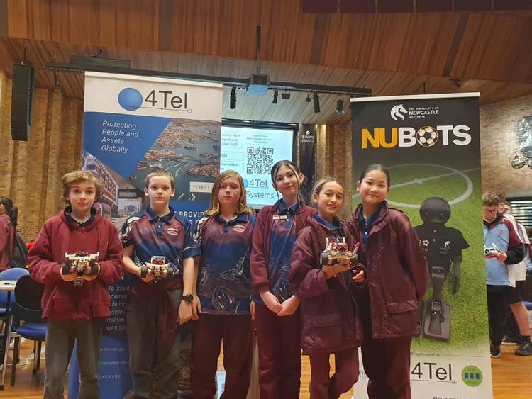 A group of students standing together holding sports trophies.